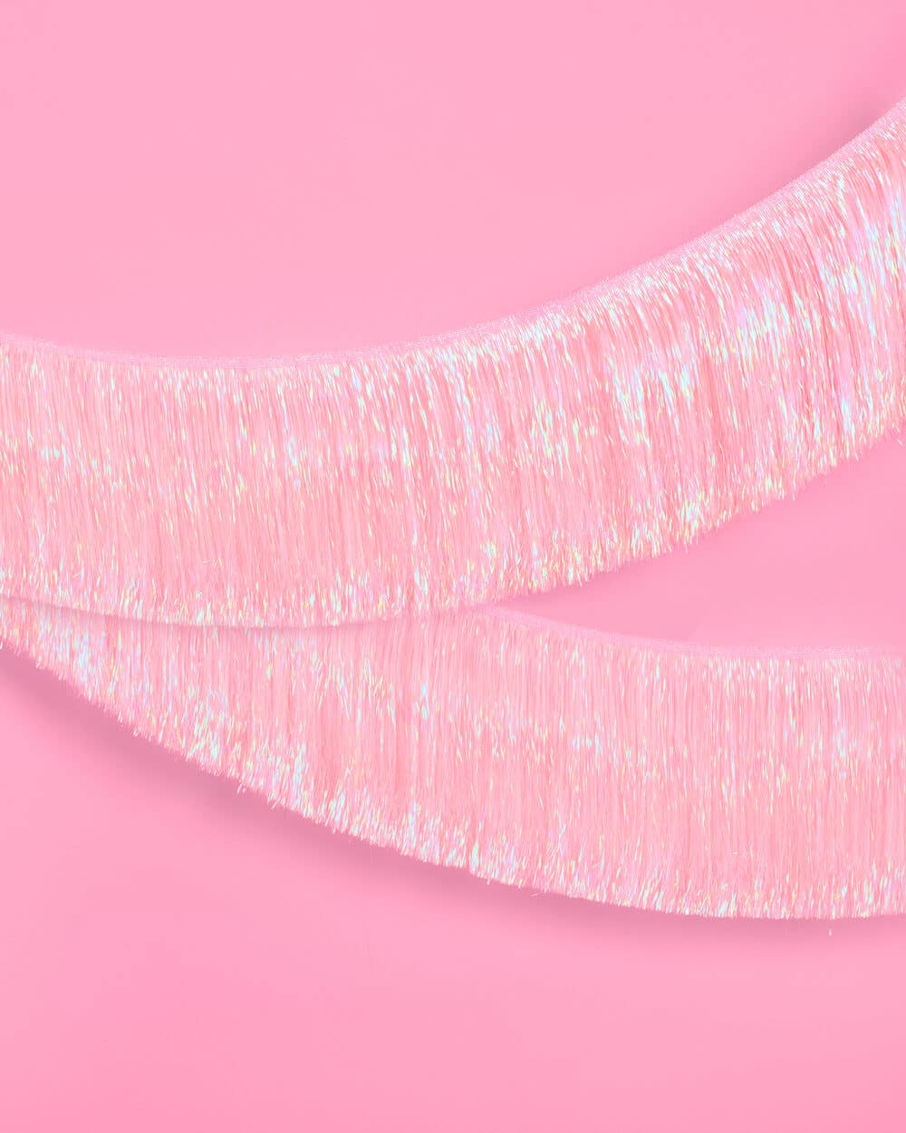 Light pink foil fringe banner hung as a party backdrop