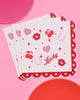 Scalloped edge cocktail napkins printed with cherries, lips, and hearts in pink foil
