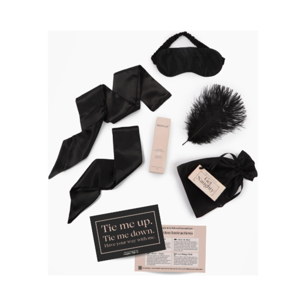 Beloved Naughty Night In Gift Set flat lay with silk ties, blindfold, feather tickler, serum and instruction card
