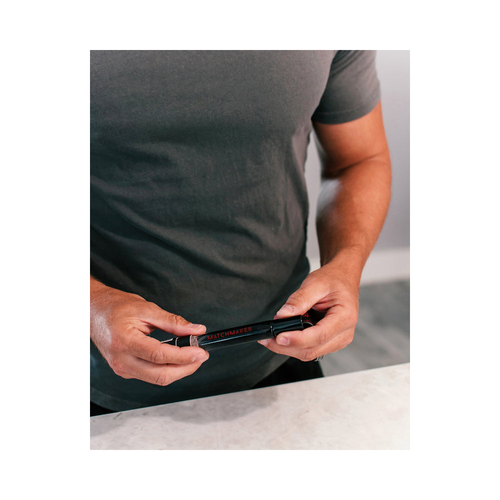 Hands holding the black Matchmaker spray vial over a countertop