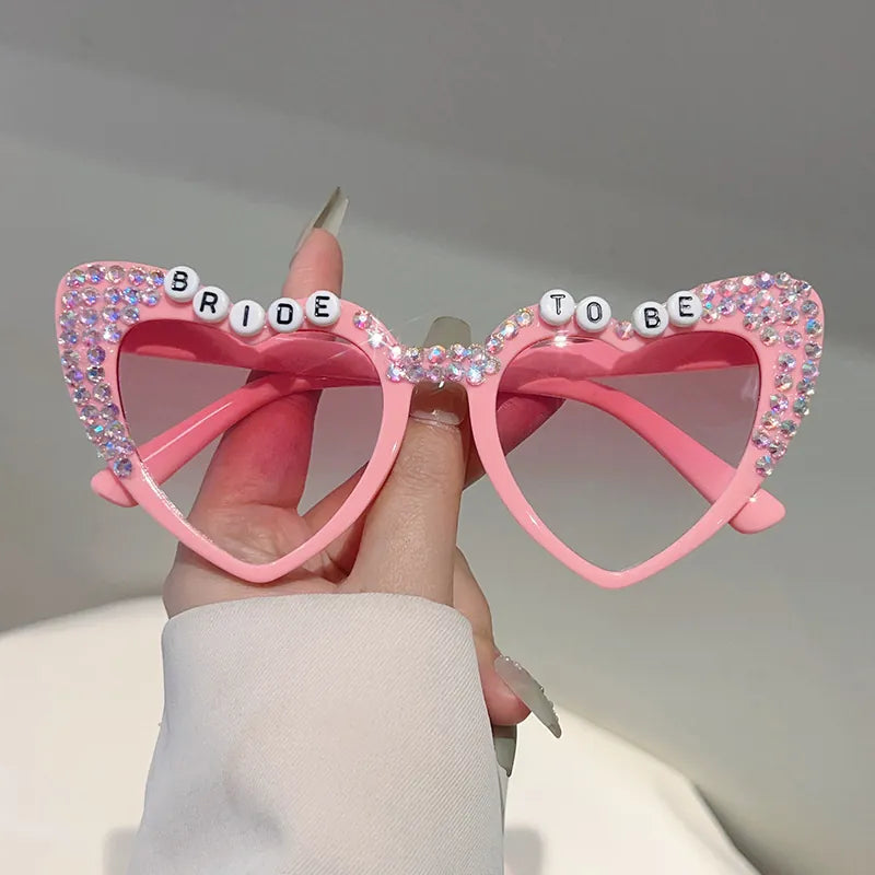 Pink heart-shaped sunglasses with rhinestone Bride To Be lettering and gradient pink lenses