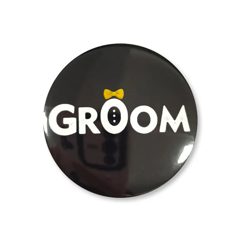 Black 58mm tinplate pin badge reading GROOM