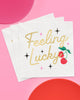 White paper napkins with gold foil Feeling Lucky lettering and cherry icons