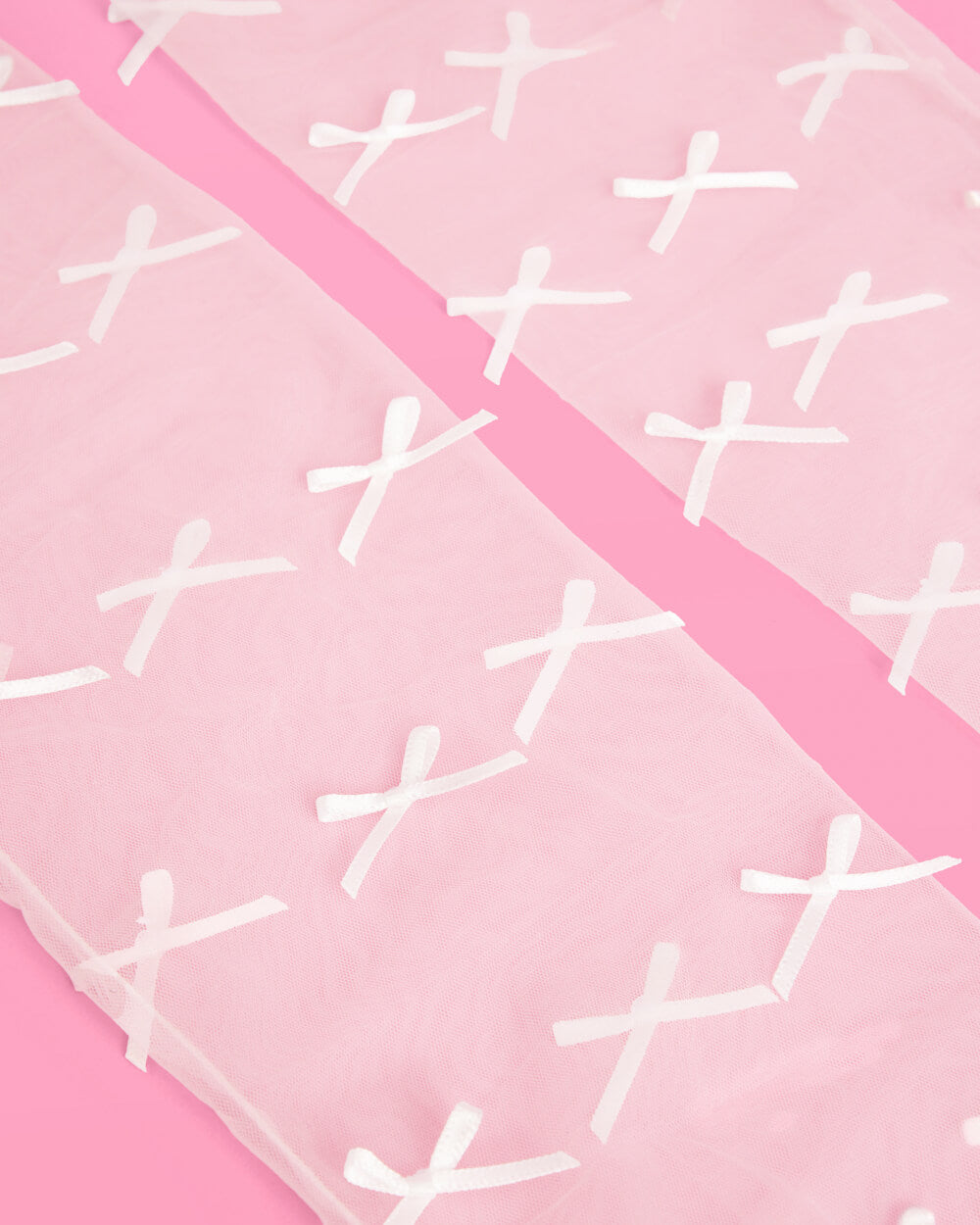 Close up of white mini satin bows on sheer organza